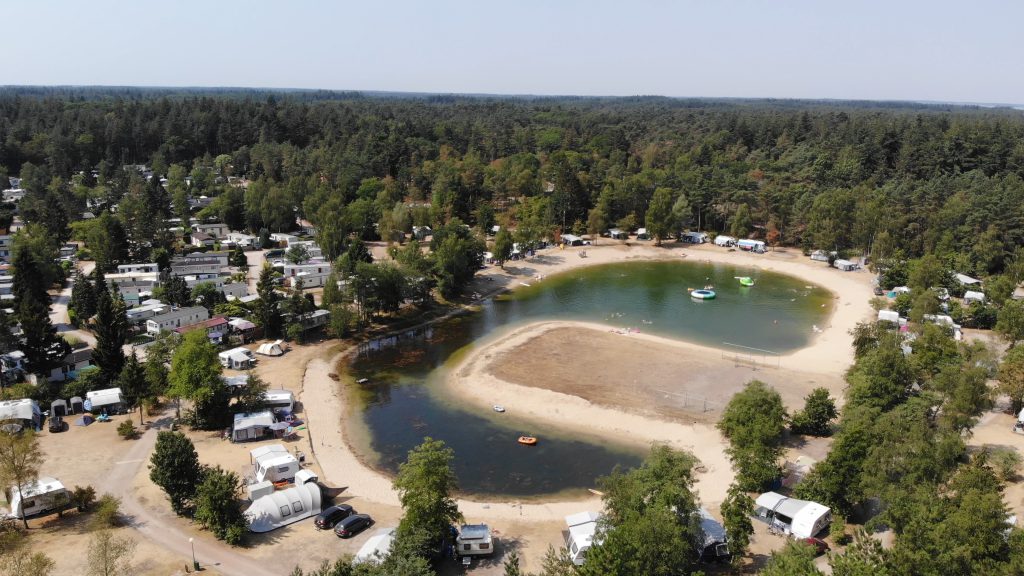 Luchtfoto van Camping de Tol in Nunspeet, omringd door weelderige bossen en een serene meer in de Veluwe-regio.